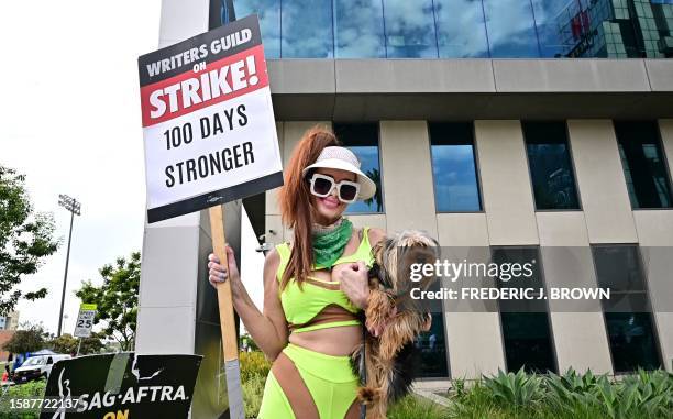 Actress Phoebe Price holds her dog and a picket sign joining members of the Writers Guild of America and the Screen Actors Guild on the picket line...