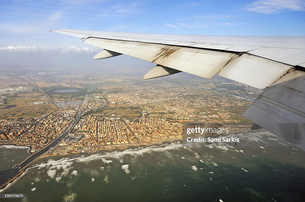 Wing of airplane flying by seacoast