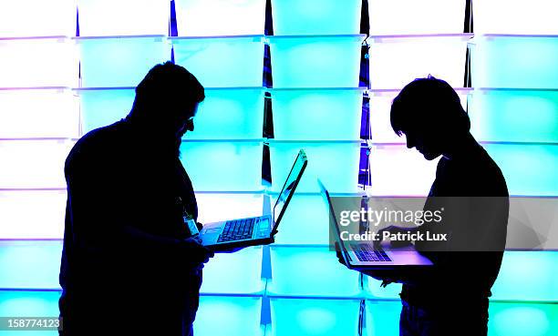 Participant hold their laptops in front of an illuminated wall at the annual Chaos Computer Club computer hackers' congress, called 29C3, on December...