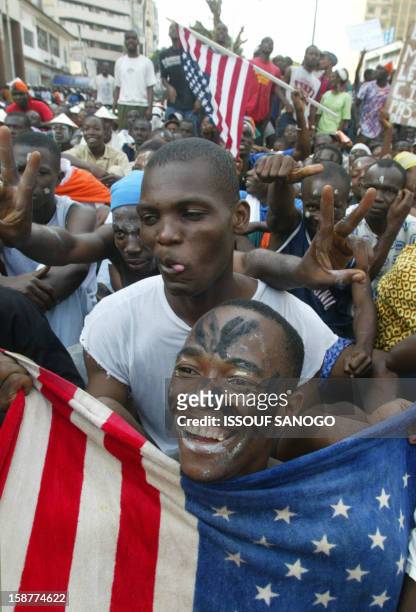 Ivorians wave the US flag in front of the US Embassy 28 January 2003 in Abidjan, where hundreds of angry youths protested against a French-brokered...