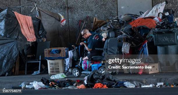 Person in a motorized wheelchair maneuvers his way past a sidewalk campsite on Broadway in Sacramento in October after a Sacramento Community...