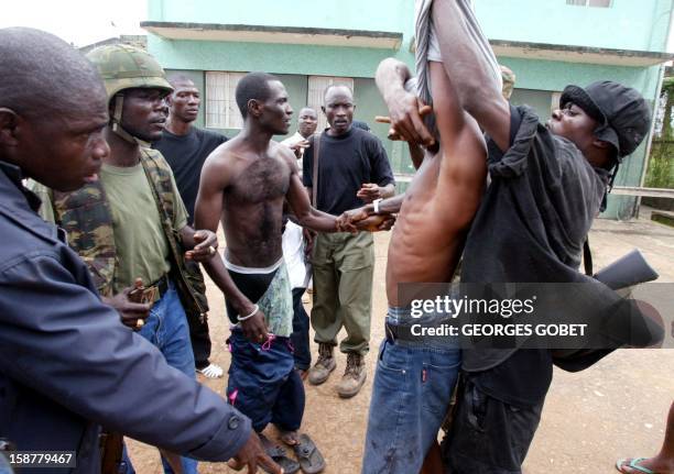 Loyalist soldiers undress prisoners arrested in Monrovia 27 June 2003 where Liberian President Charles Taylor's forces took control of the city....