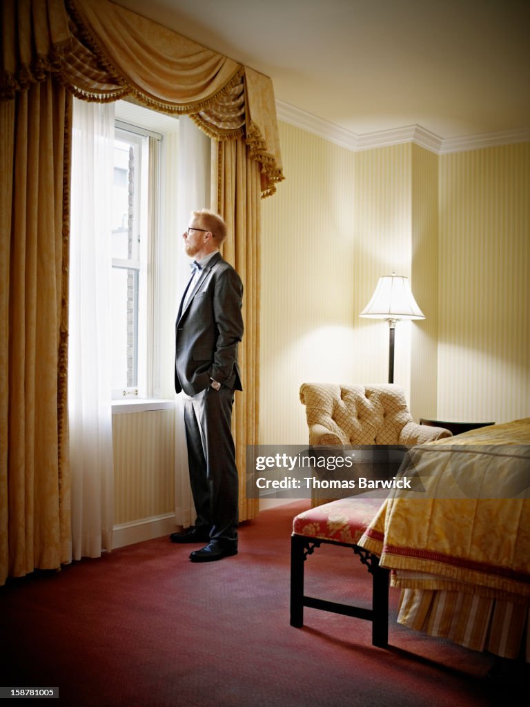 Businessman looking out window of hotel suite