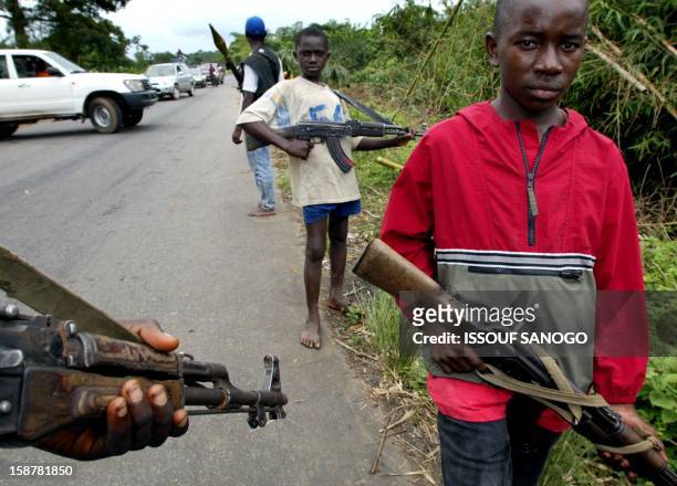 Young rebels of the Liberians United for Reconciliation and Democracy stand guard, 19 August 2003, at the southern entry to the river Po bridge where...