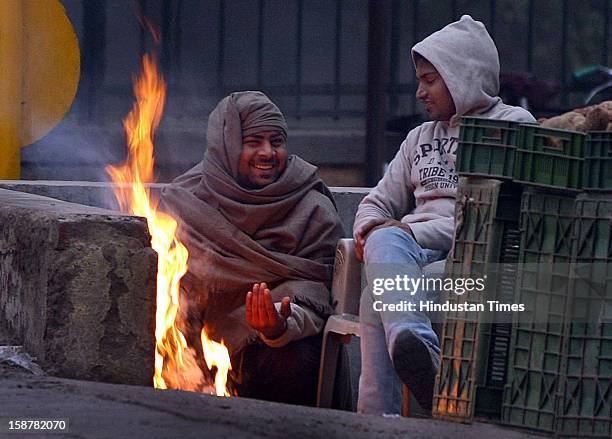 The men feel comfortable near the fire the cold and foggy weather at Myur Vihar, on December 28, 2012 in New Delhi, India. While the maximum...