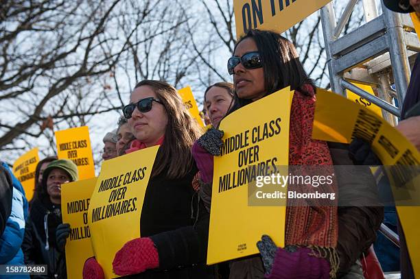 Protesters hold signs that read " Middle Class Over Millionaires" on the grounds of the U.S. Capitol in Washington, D.C., U.S., on Friday, Dec. 28,...