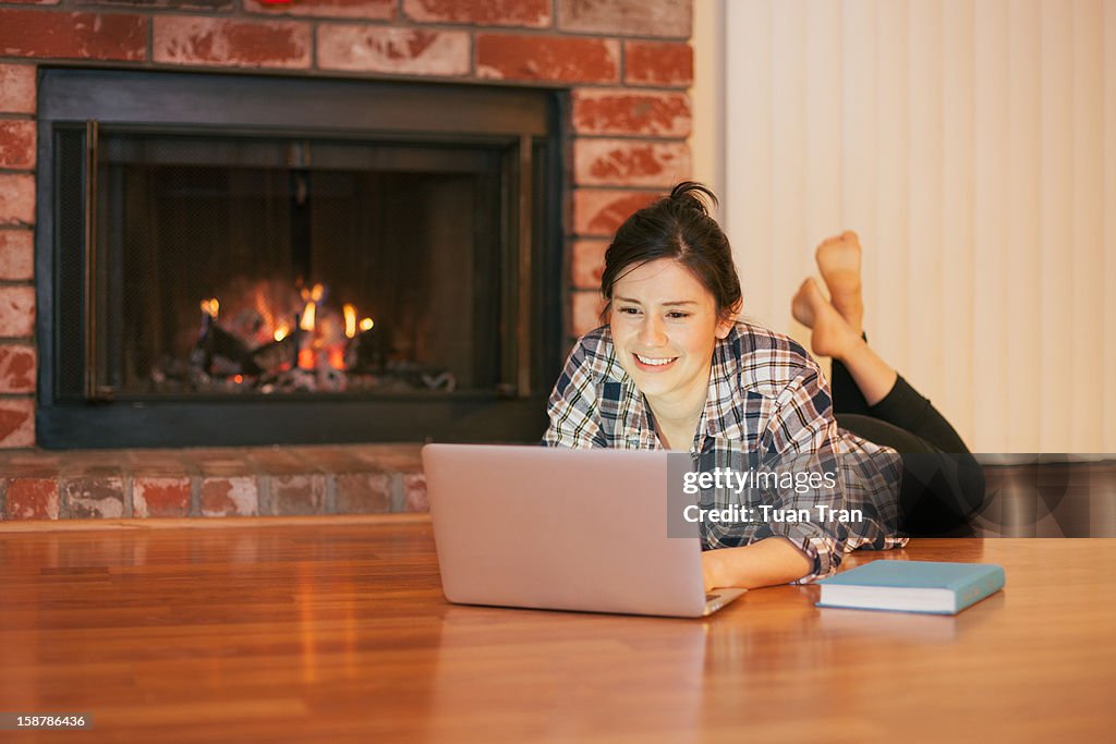 Woman using laptop by the fireplace