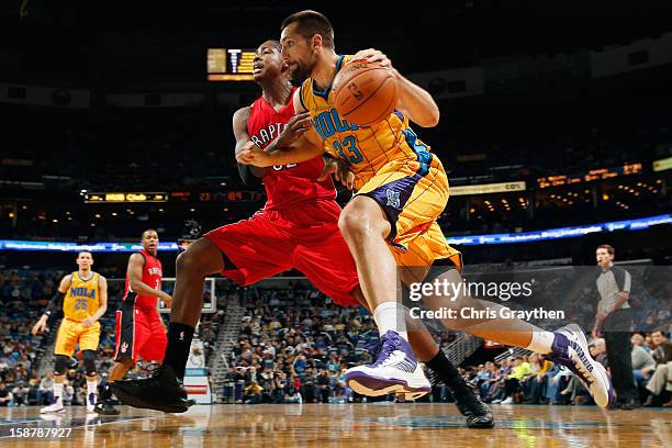 Ryan Anderson of the New Orleans Hornets drives the ball arount Ed Davis of the Toronto Raptors at New Orleans Arena on December 28, 2012 in New...