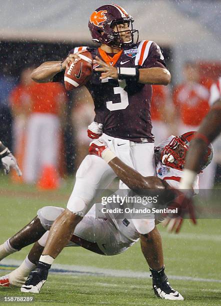 As Rutgers defensive lineman Jamil Merrell hangs on to him in the rain, Virginia Tech quarterback Logan Thomas calmly looks to throw in the Russell...