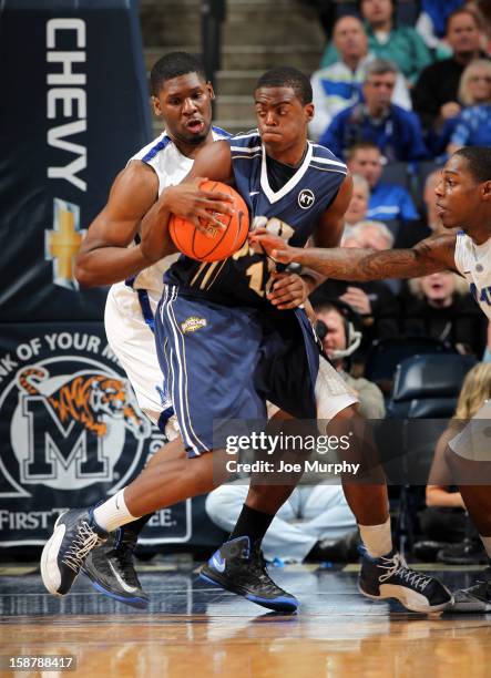 Shawn Glover of the Oral Roberts Golden Eagles drives between Adonis Thomas and Antonio Barton of the Memphis Tigers on December 28, 2012 at...