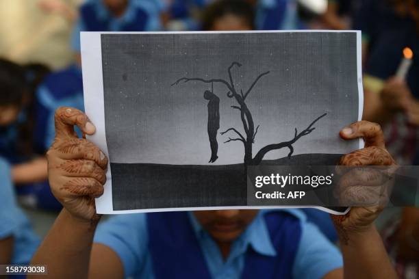 Indian schoolgirl holds a placard with an image of a hanging man during a rally in Ahmedabad on December 29 after the death of a gangrape victim from...