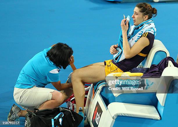 Andrea Petkovic of Germany is checked by a trainer after injurying her right knee in her group A singles match Ashleigh Barty of Australia during day...