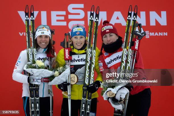 Charlotte Kalla of Sweden, Kikkan Randall of the United States and Justyna Kowalczyk of Poland celebrate at the podium after the Women's 3.1km Free...