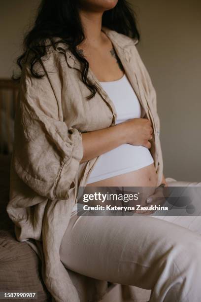 a beautiful young pregnant woman with tattoos inside a wooden house - umstandskleidung stock-fotos und bilder