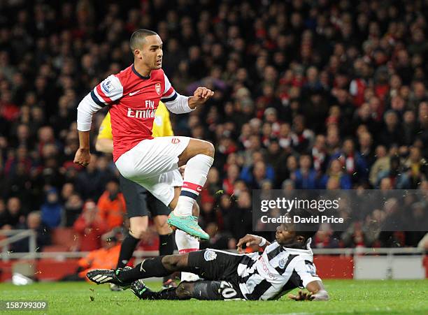 Theo Walcott scores his 2nd goal under pressure from Gael Bigirimana of Newcaste during the Barclays Premier League match between Arsenal and...