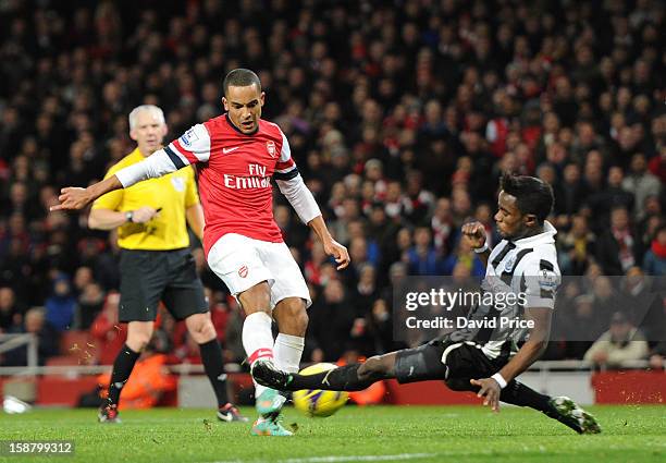 Theo Walcott scores his 2nd goal under pressure from Gael Bigirimana of Newcaste during the Barclays Premier League match between Arsenal and...