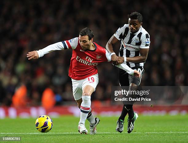 Santi Cazorla of Arsenal is challenged by Gael Bigirimana of Newcastle during the Barclays Premier League match between Arsenal and Newcastle United...