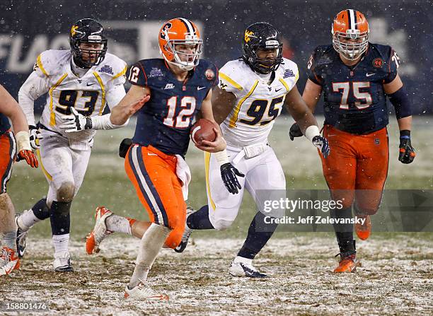 Ryan Nassib of the Syracuse Orange scrambles in front of Christian Brown of the West Virginia Mountaineers in the New Era Pinstripe Bowl at Yankee...