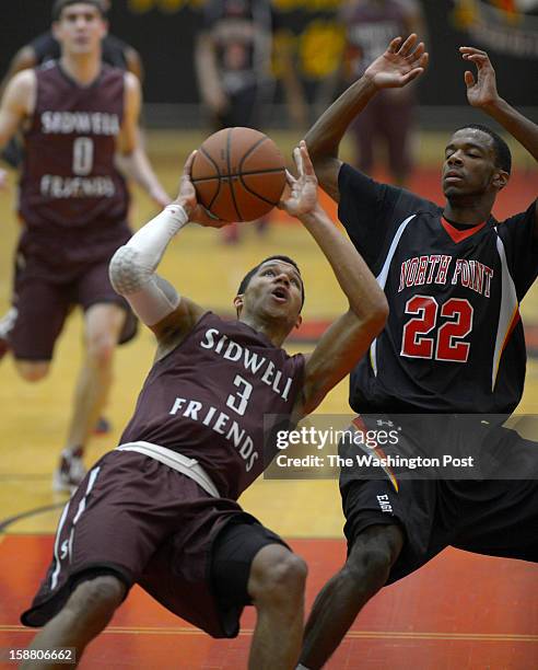 Sidwell's Josh hart, left, looses his footing under the basket on a fast break defended by North Point's Daylin Davis as North Point plays Sidwell...