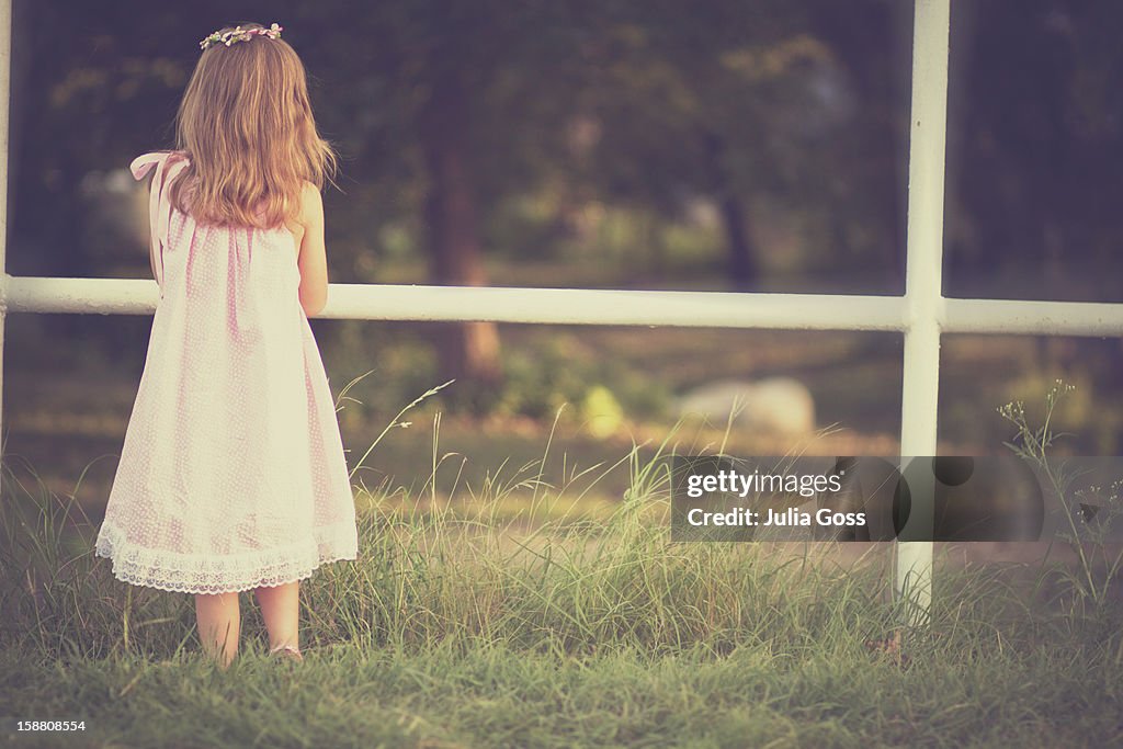 Young girl standing by a fence