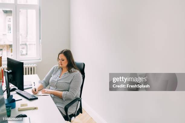 smiling plus size woman working on desktop computer - administrative professional stock pictures, royalty-free photos & images