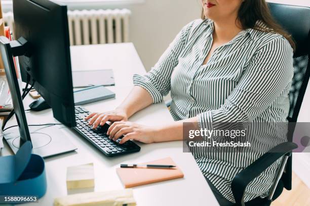 anonymous plus size businesswoman writing a report on a desktop pc in her office - administrative professional stock pictures, royalty-free photos & images