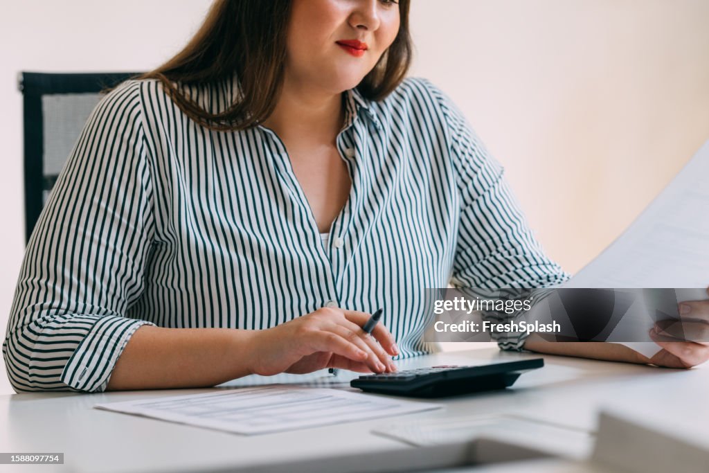 Anonymous Businesswoman Analyzing Financial Reports Using a Calculator