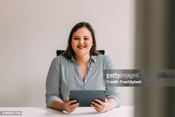 portrait of a happy overweight woman watching something on a digital tablet - administrative professional stock pictures, royalty-free photos & images