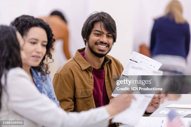 diverse polling place volunteers discuss the paper ballot - bi partisan stock pictures, royalty-free photos & images