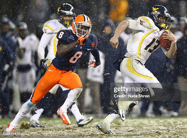 Andrew Buie of the West Virginia Mountaineers runs the ball against Keon Lyn of the Syracuse Orange during the New Era Pinstripe Bowl at Yankee...