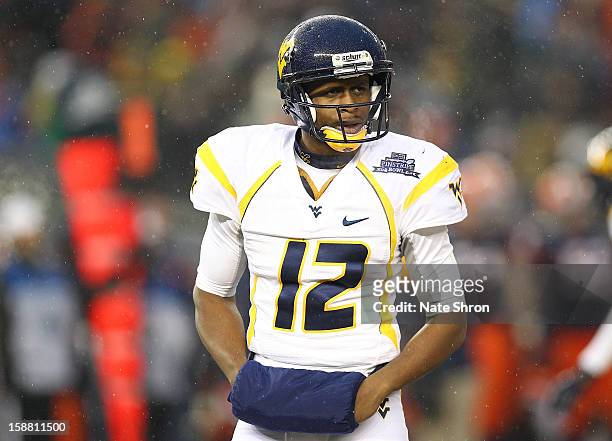 Quarterback Geno Smith of the West Virginia Mountaineers looks on during the game against the Syracuse Orange during the New Era Pinstripe Bowl at...