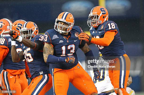 Deon Goggins, Siriki Diabate and Dyshawn Davis of the Syracuse Orange celebrate on the field during the game against the West Virginia Mountaineers...