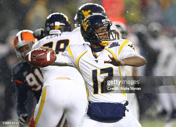 Quarterback Geno Smith of the West Virginia Mountaineers passes the ball against the Syracuse Orange during the New Era Pinstripe Bowl at Yankee...