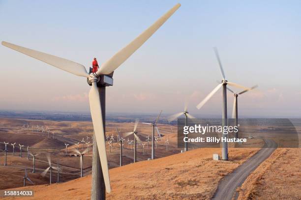 worker standing on wind turbine at wind farm - energia eolica foto e immagini stock