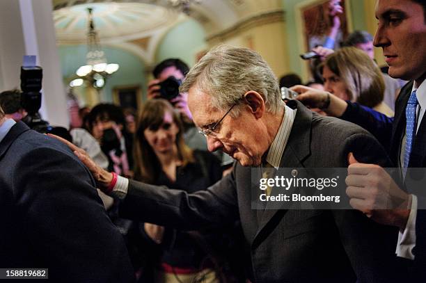 Senate Majority Leader Harry Reid, a Democrat from Nevada, is escorted through a crowd of reporters as he walks to the Senate Floor following a party...