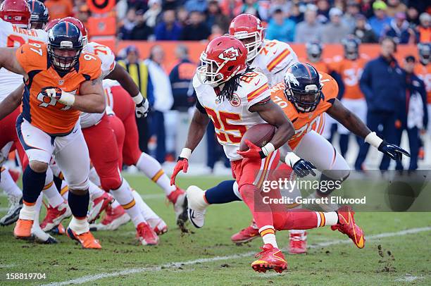 Jamaal Charles of the Kansas City Chiefs runs the ball against Justin Bannan and Malik Jackson of the Denver Broncos during the game at Sports...