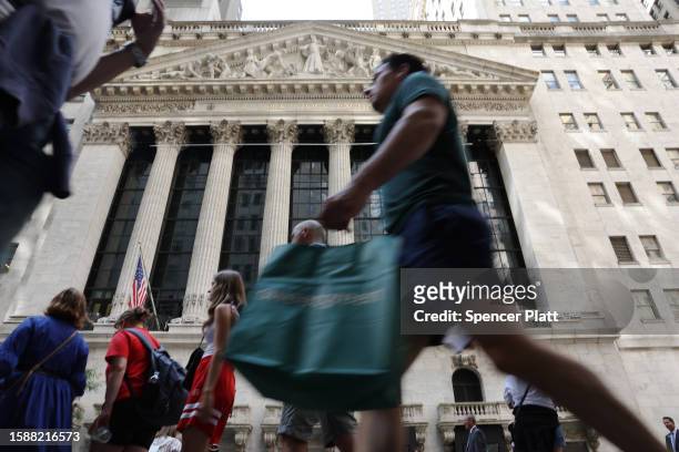 People walk by the New York Stock Exchange on August 02, 2023 in New York City. The Dow fell over 300 points in trading following news Fitch...