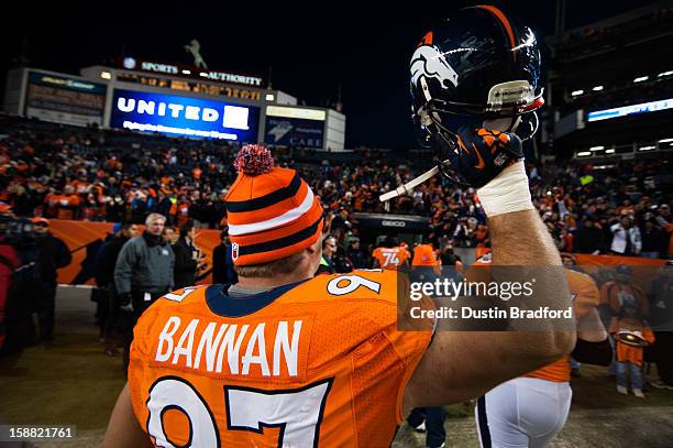 Defensive tackle Justin Bannan of the Denver Broncos holds his helmet in the air as he walks off the field to loud cheers after securing the seed in...