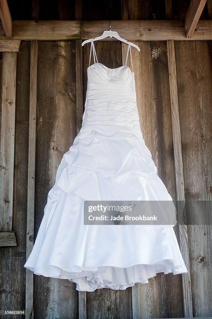 Wedding dress hanging against old wood