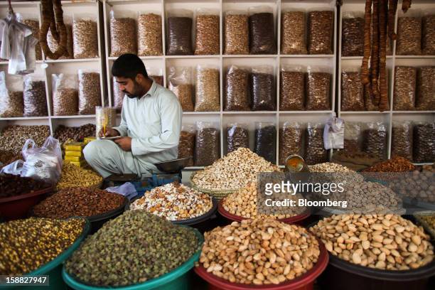 Vendor selling dried fruits and nuts writes in a book at a market in Islamabad, Pakistan, on Sunday, Dec. 30, 2012. Pakistan’s economy will probably...
