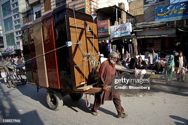 Laborer pulls a handcart loaded with cabinets through a market in Rawalpindi, Pakistan, on Sunday, Dec. 30, 2012. Pakistan’s economy will probably...