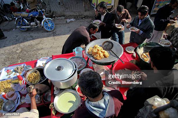 Vendors prepare food at a market in Rawalpindi, Pakistan, on Sunday, Dec. 30, 2012. Pakistan’s economy will probably expand 3.5 percent in the 12...