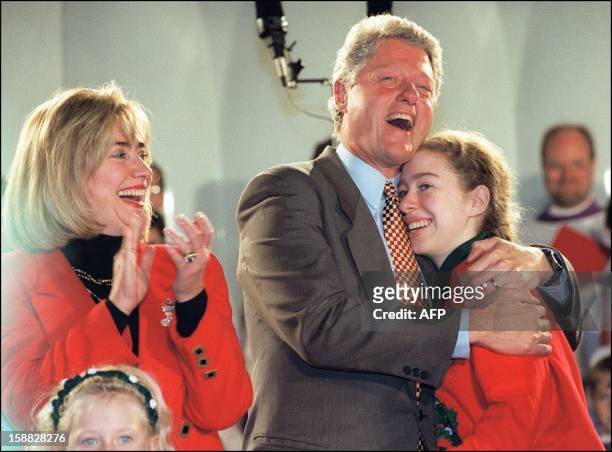 President Bill Clinton in a picture taken 07 December 1994 in Washington, DC., hugs his daughter Chelsea as First Lady looks on after singing...