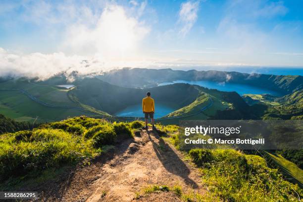 man on top of a mountain admiring lagoa das sete cidades, azores - admirar a vista imagens e fotografias de stock