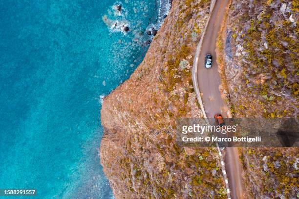 cars driving on tiny coastal road - main road stock pictures, royalty-free photos & images