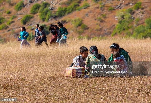 Young children have a picnic in the beautiful landscape around the village Chimi Lhakhang in the Punakha Valley with its temple, monastery is...