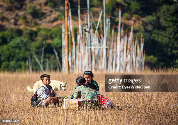 Young children have a picnic in the beautiful landscape around the village Chimi Lhakhang in the Punakha Valley with its temple, monastery is...