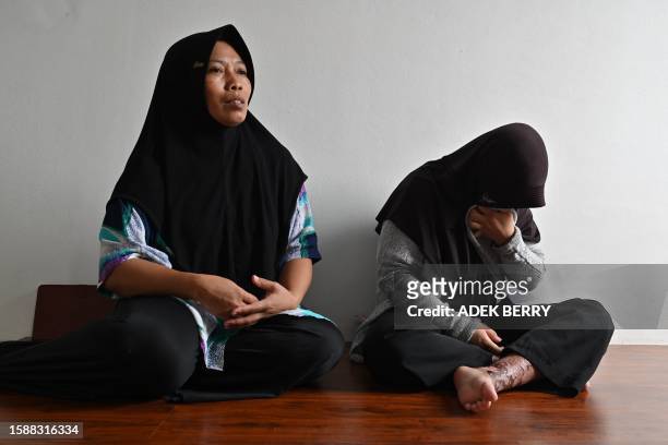 This picture taken on July 27, 2023 shows Eni Sopiah speaking next to her daughter Siti Khotimah, who suffered from physical abuse by her employer...