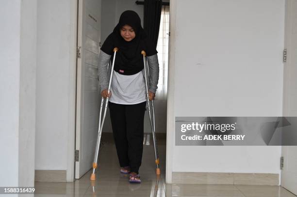 This picture taken on July 27, 2023 shows Siti Khotimah walking with crutches after the physical abuse she suffered by her employer while working as...