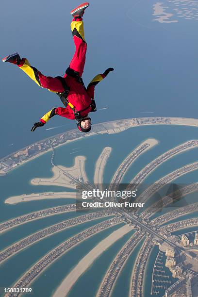 skydiver flying upside down above the dubai palm - skydiving palm stock pictures, royalty-free photos & images